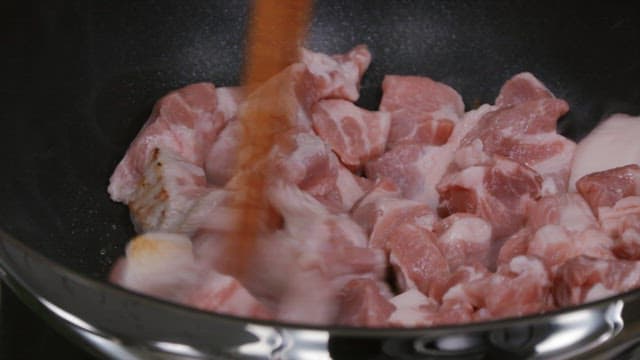 뜨거운 프라이팬에서 젓가락으로 돼지고기를 볶는 모습