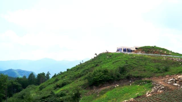 White building located on top of a lush mountain