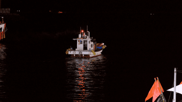 Fishing boats heading out onto water at night