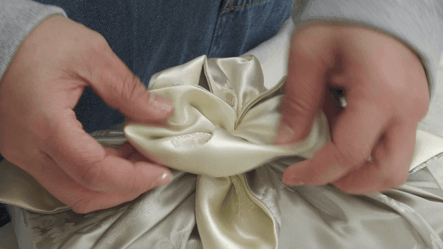 Hands trimming gift wrapping knots with traditional fabric