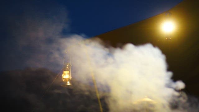 연기가 피어오르는 어두운 밤을 밝히는 캠핑용 랜턴