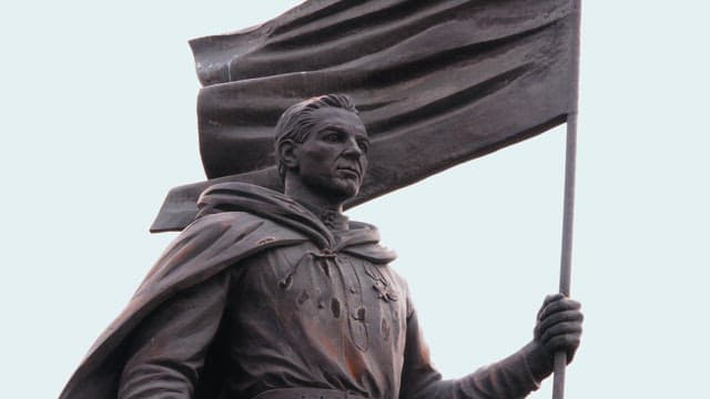 흐린 하늘 아래 망토를 두른 남자의 역사적 동상