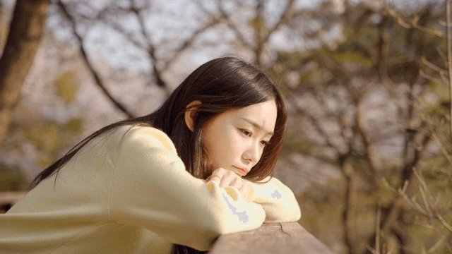 공원 난간에 기대어 생각에 잠긴 여성