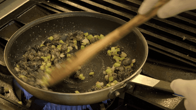 Chef cooking vegetables and snails in pan
