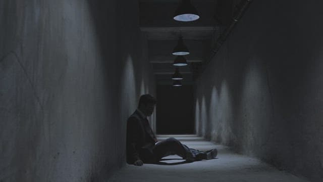 어두운 지하 복도에서 비틀거리며 일어나는 남자