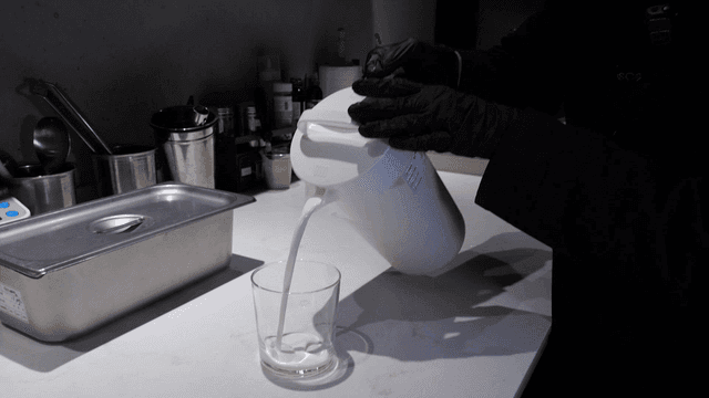 Pouring milk into a glass on a kitchen counter
