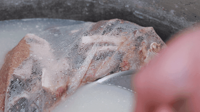Beef bones in milky broth strainer inside pot