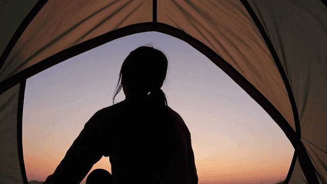 일출 시 텐트 안의 사람 실루엣