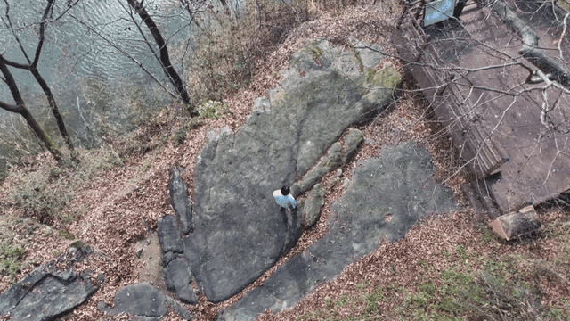 Person standing on a large rock by a river