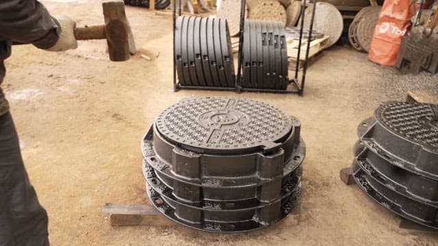 공장에서 맨홀 뚜껑을 다루는 작업자