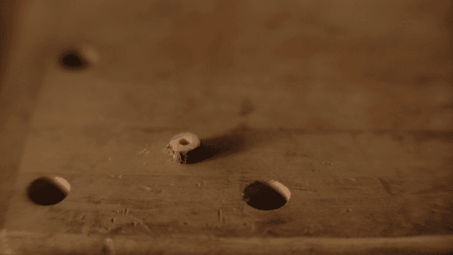 장갑 낀 손이 나무 원반을 정리하는 모습