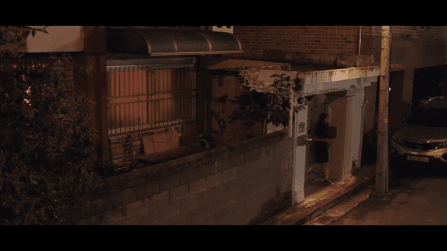 Woman standing outside a house at night
