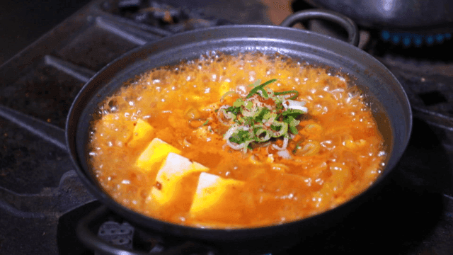 Red pepper powder sprinkled on kimchi stew boiling in pot