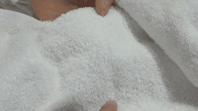 부드러운 흰 수건의 작은 오염을 찾는 손