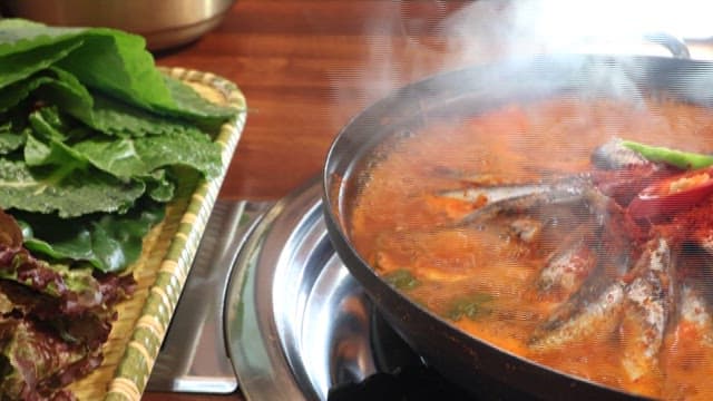 Spicy fish stew boiling on a restaurant table