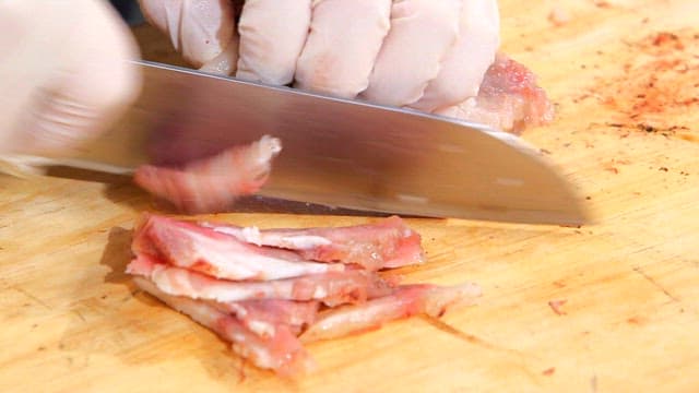 Cutting cooked beef with gloved hands
