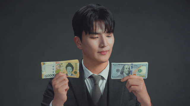 손에 든 한국 원화를 보고 미소짓는 남자