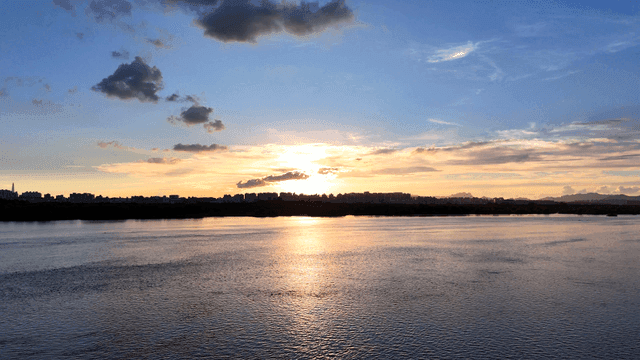 Sunset over a calm river with city skyline