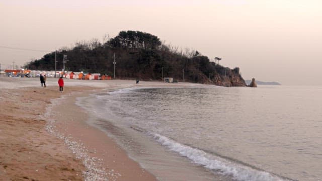 People walking along the peaceful beach with waves