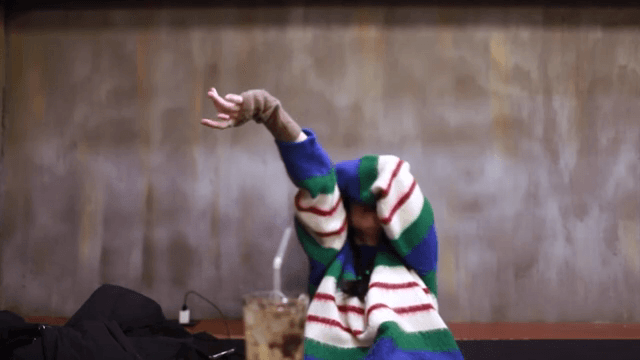 실내에서 스트레칭을 하는 화려한 스웨터를 입은 여성