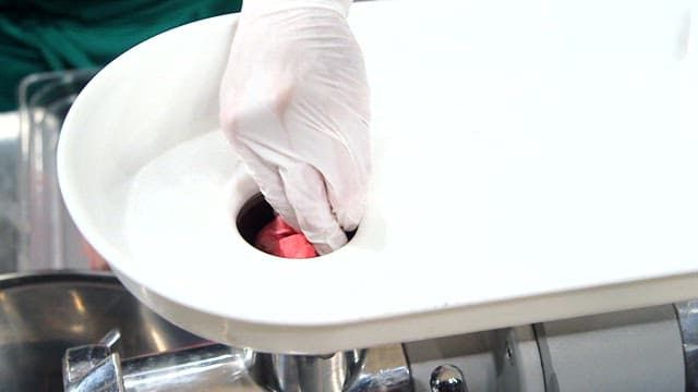 Ground beef being processed in a grinder