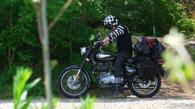 Motorcyclist starting off on a tree-lined road