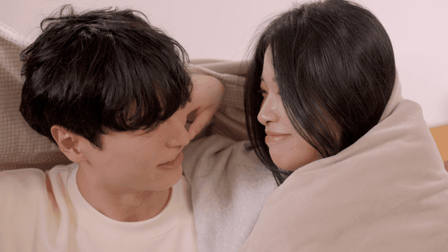 이불 아래에서 함께 웃는 커플
