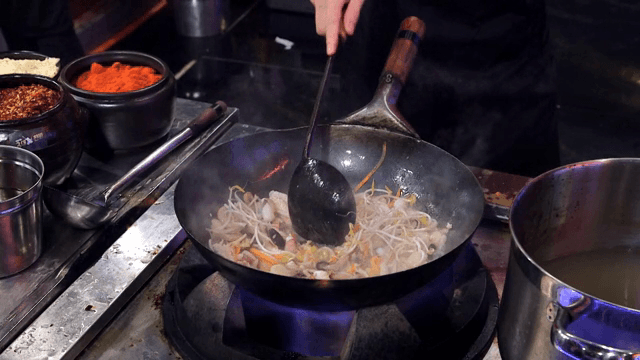 Stir-frying vegetables and seafood in a hot wok