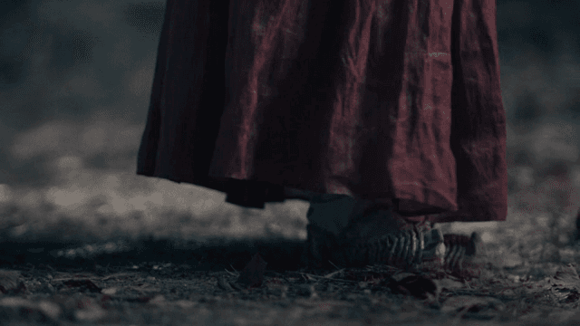 A person walking wearing traditional Korean clothing and straw shoes