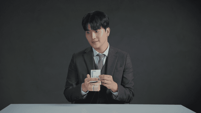 만족스러운 표정으로 책상에서 돈을 세는 정장 입은 남자