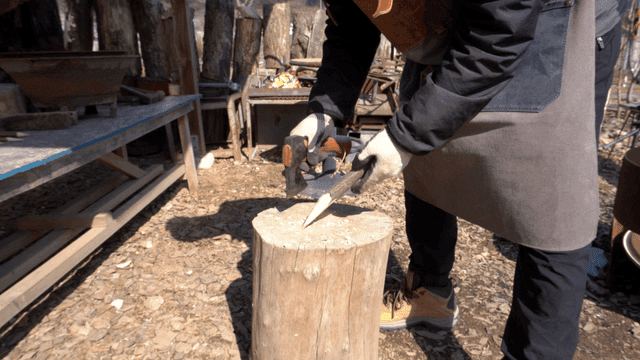 야외에서 도끼로 나무를 날카롭게 다듬는 목공예가