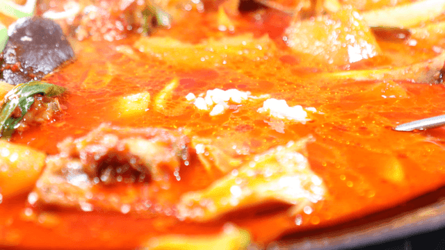 Spoonful of rice dipped in spicy chicken stew broth