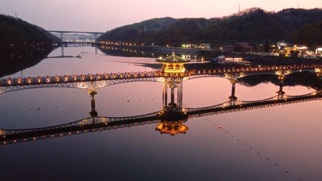 Illuminated bridge over calm river at night