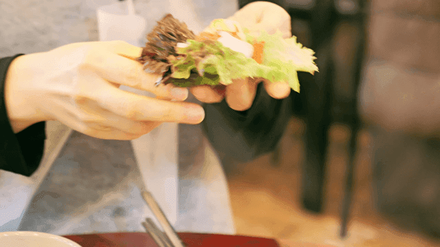 Person preparing lettuce wraps with dakgalbi