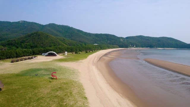 Peaceful Beach with Green Hills and Recreational Facilities