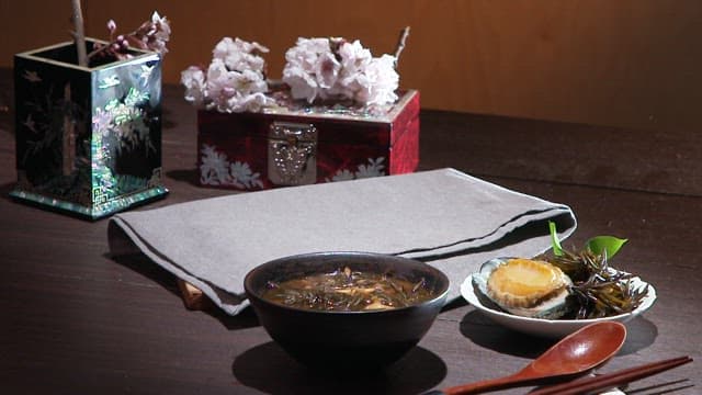 Neatly arranged kimbap, soup, and side dishes on a wooden table