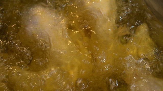 Raw chicken frying in hot oil in a kitchen