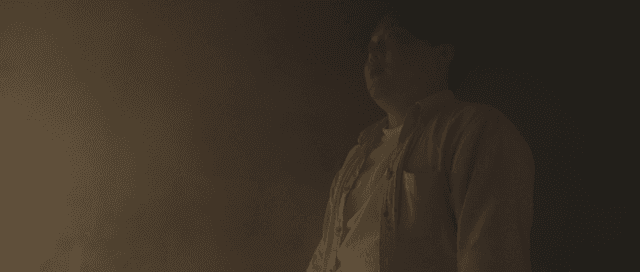 어두운 곳에 서 있는 얼굴에 상처난 남자