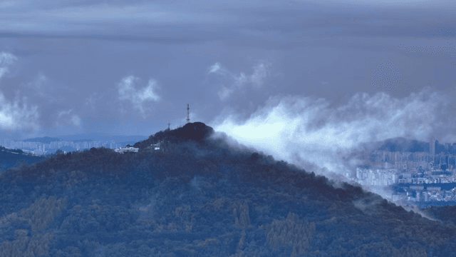 A mountain with clouds and a cityscape