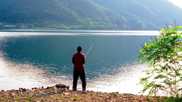 Man fishing at a serene lake in the morning