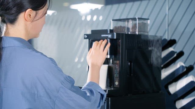 Woman making coffee from office coffee machine