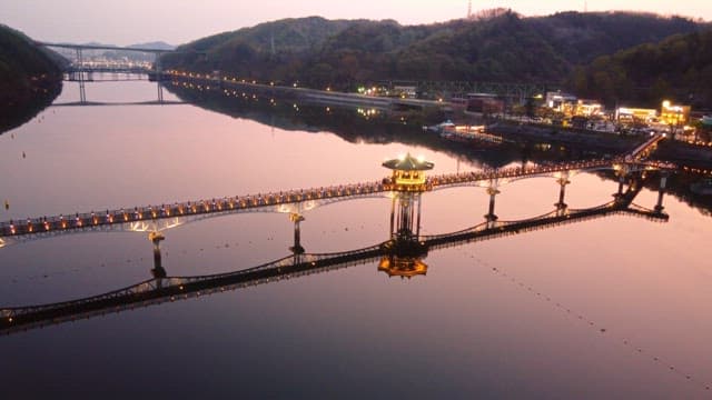 Illuminated bridge over calm river at night