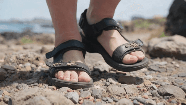 Feet in sandals walking on rocky beach