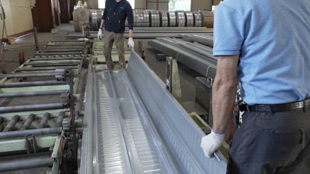 Workers handling metal sheets in a factory