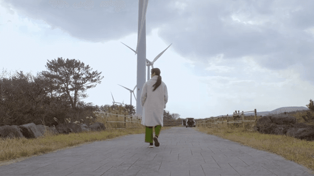 풍력 터빈 근처를 걷는 여성의 뒷모습