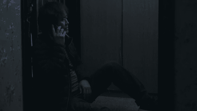 Man sitting in front of a door and calling someone