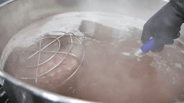 Hands stirring broth in large pot