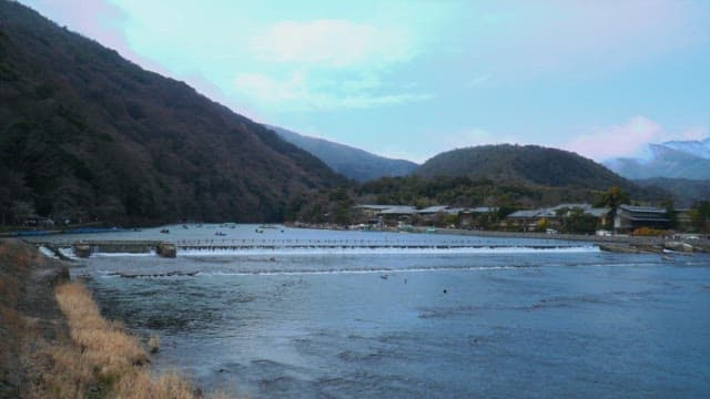 Riverside village with green mountains under a blue sky