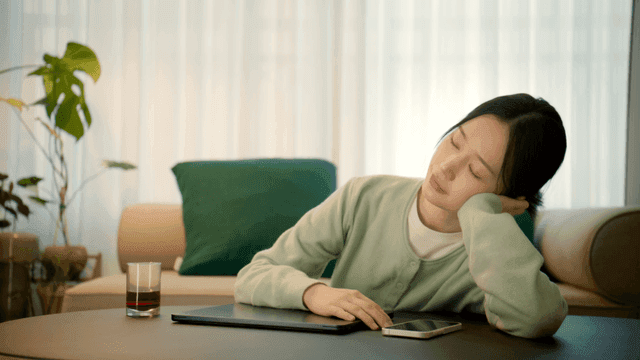 Woman working on her laptop at home and slumping down on her desk