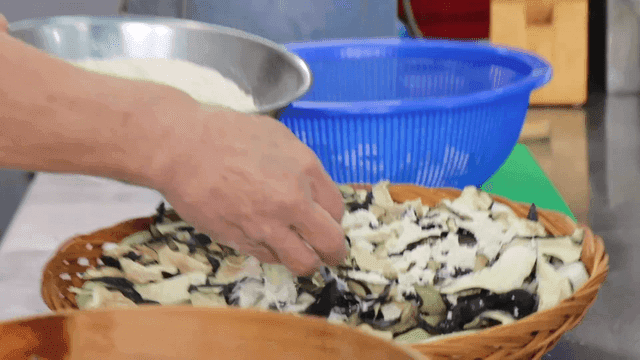 말린 가지 위에 메밀 가루를 뿌리는 요리사